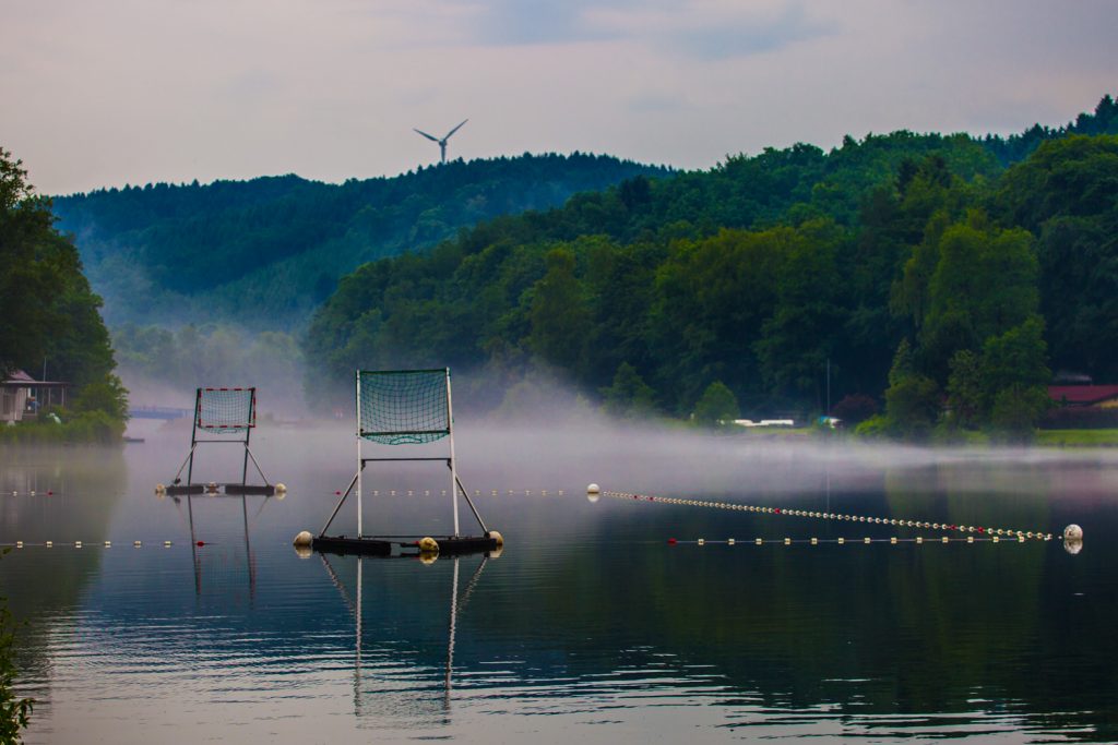 Bild des Sees im Nebel. In der Mitte das aufgebaute Kanupolo-Spielfeld